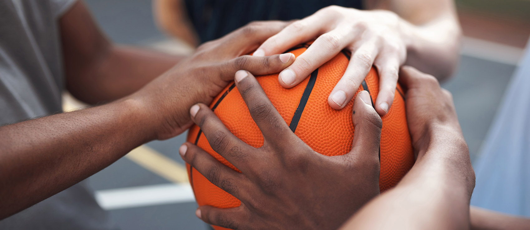 Close-up of multi-ethnic men's hands on a basketball