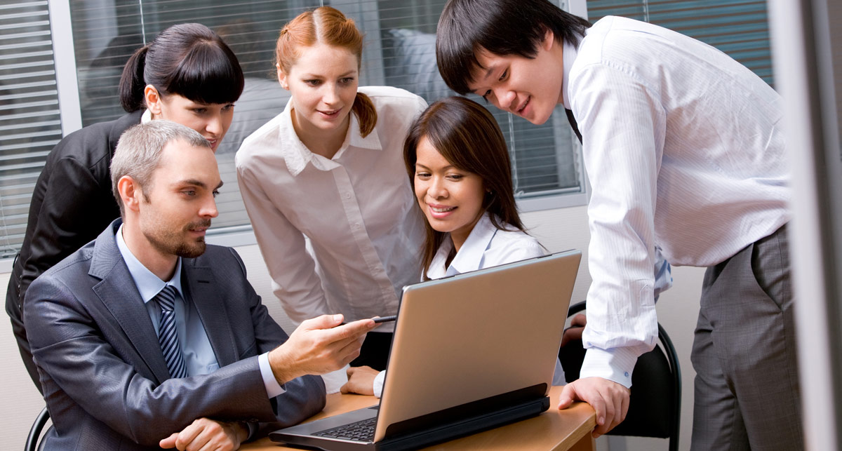 Group of young professionals looking at a laptop screen in an office