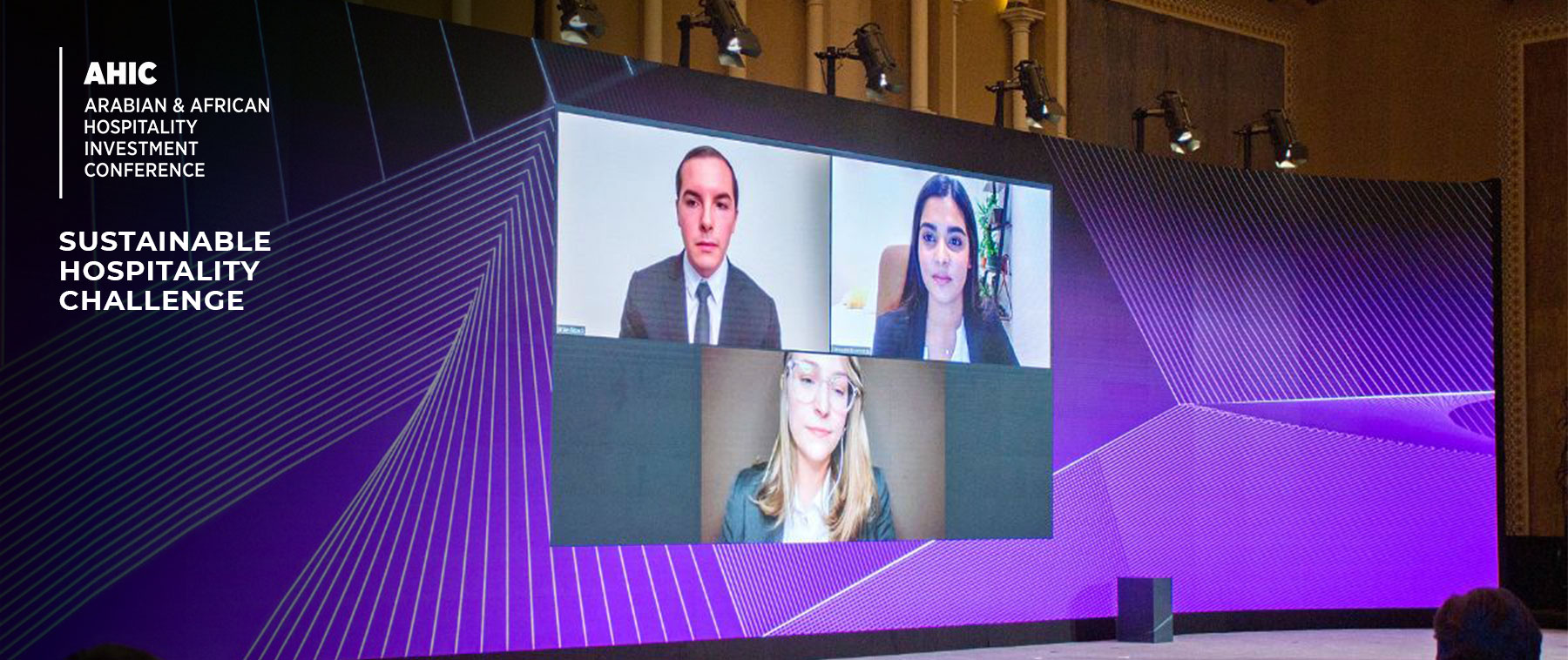 Large screen displaying a video conference with three participants