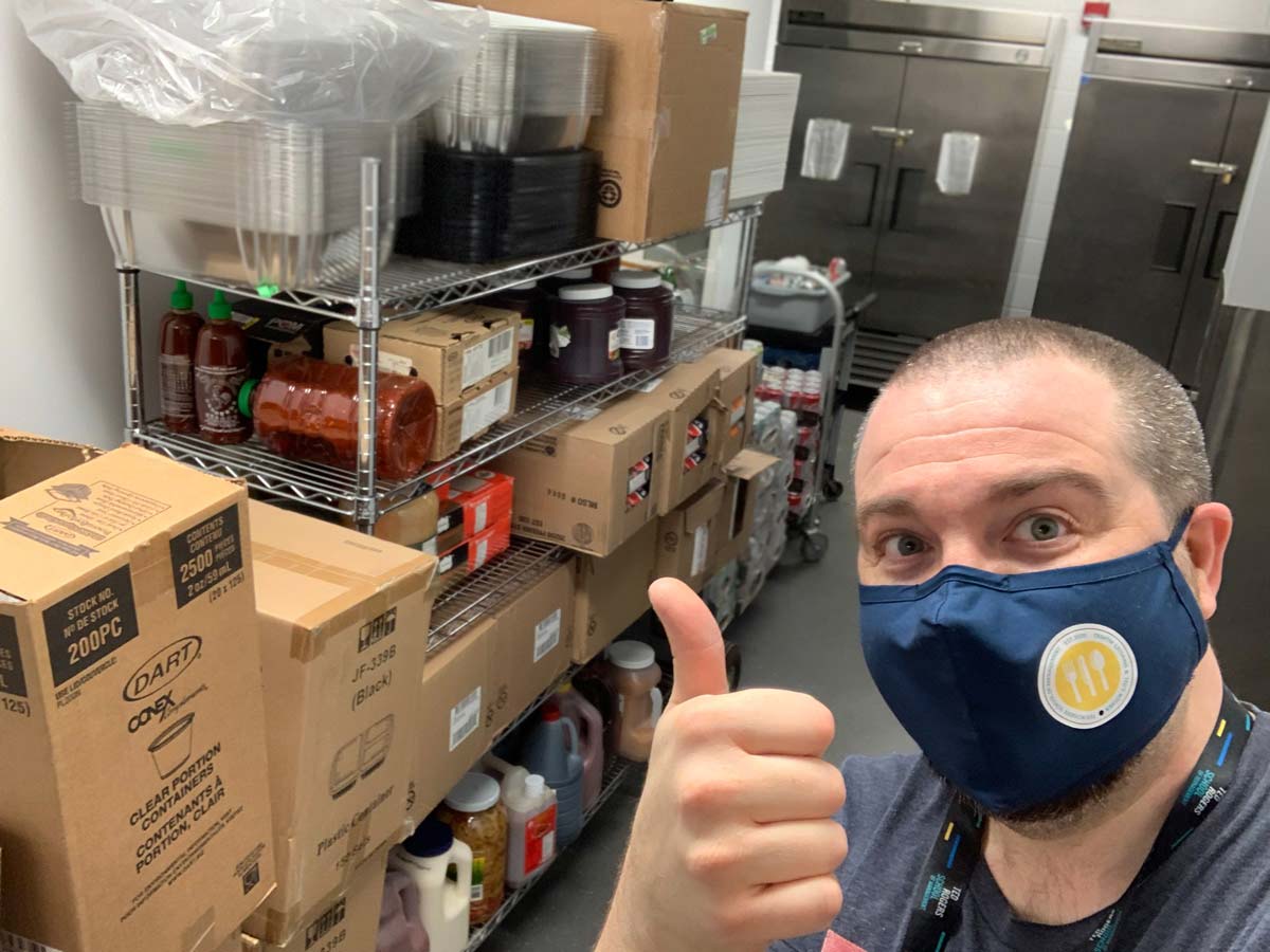 Chef Tommy McHugh giving a thumbs up in front of shelves full of packaged foods